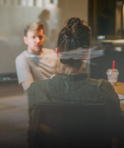 Image d'une femme de dos face à un homme. Cette image représente le sujet de l'atelier pour préparer son pitch, travaille son message, le tester et l'ajuster.