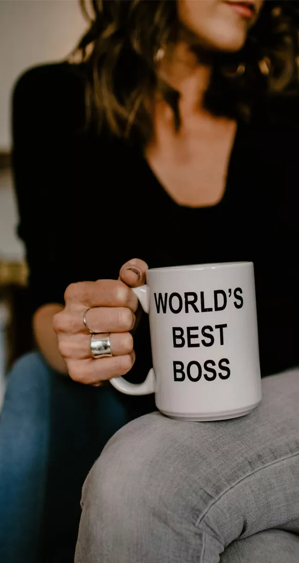 Image d'une femme tenant sa tasse de café sur laquelle est écrit "World's best boss" pour illustrer le cas d'Amélie S, avocate associée accompagnée par Compte sur toi