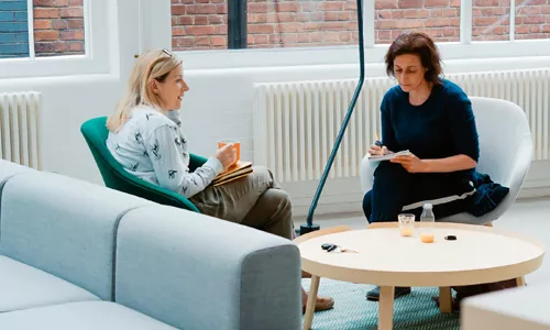 Image de 2 femmes discutant autour d'une table. Image représentant le dialogue clair nécessaire pour la négociation